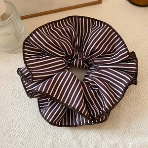 Détail d'un chouchou en dentelle à rayures marron et blanc avec une texture soignée