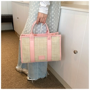 Detail of hand-woven straw tote with pink leather handle and embossed logo brand plate