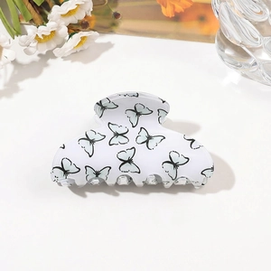 Detail of white acrylic hair claw clip featuring delicate blue butterfly prints