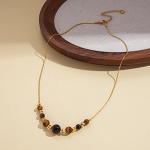 Close-up of vintage sun pendant necklace with tiger eye beads and gold chain detail
