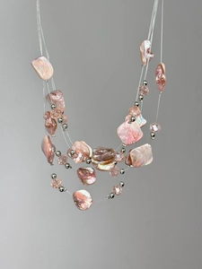 Détail d'un collier bohème multicouche avec perles de cristal roses et nacre naturelle