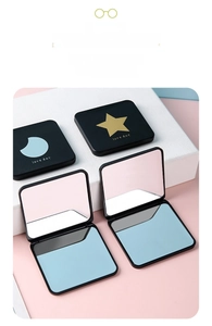 Detail of black pocket makeup mirror with gold star pattern and dual-sided folding design