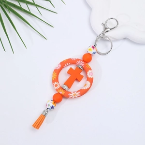 Detail of orange silicone cross keychain with floral ring, colorful beads, and tassel