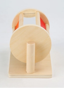 Close-up of wooden spinning drum Montessori toy with red and orange panels for sensory play