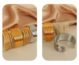 Detail of minimalist wave-patterned bangles in gold and silver finish on stone