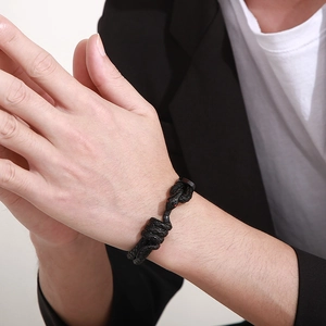 Close-up of men's black braided leather bracelet with red-eyed snake head buckle