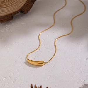 Minimalist gold stainless steel necklace with geometric teardrop pendant on white stone