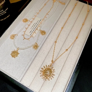 Elegant pearl choker and gold sun pendant necklace set in a luxury jewelry gift box
