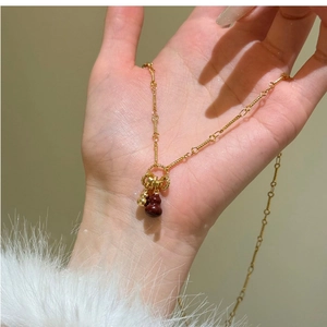 Macro shot of gold gourd pendant necklace with red agate stone on minimalist fine chain
