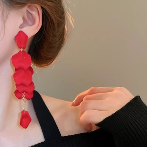 Detail of elegant red floral tassel earrings worn by a model with gold chain links