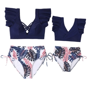 Detail of ruffled navy blue bikini tops and tropical leaf print bottoms for mother and child