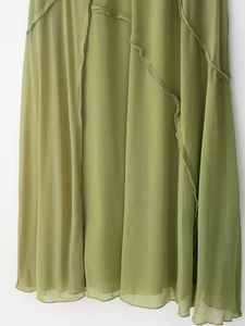 Dettaglio dell'abito in chiffon verde con eleganti volant e texture fluida e leggera