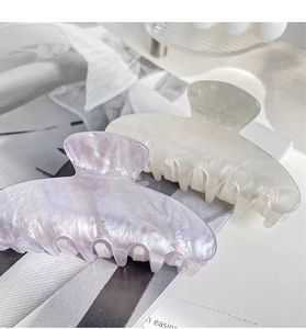 Detail of large acetate hair claws with pearlescent finish and subtle glitter accents