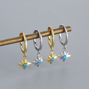 Detail of gold and silver starburst earrings with blue opal center on metal bar