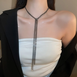 Dettaglio di una collana a più strati con nappe argento indossata su un abito nero