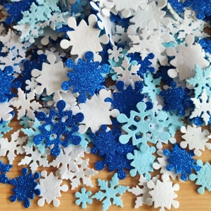 Close-up of glittery blue and white foam snowflake stickers on a wooden surface