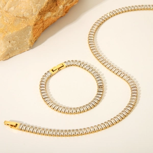 Gold stainless steel jewelry set with rectangle zircons on a natural stone background