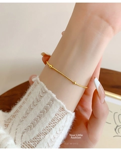 Close-up of a delicate gold snake chain bracelet with three beads on a model's wrist