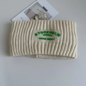 Nahaufnahme von cremefarbenem Strickstirnband mit grüner Stockholm-Bestickung
