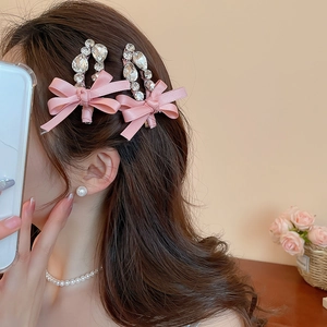 Gros plan de barrettes à nœuds roses en satin avec strass portées sur les cheveux fins