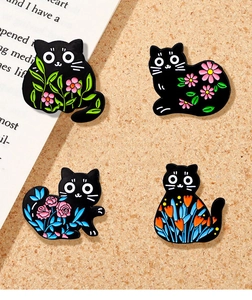 Set of four black cat enamel pins featuring colorful floral patterns on a cork background