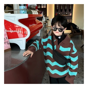 Detail showing wavy knit pattern and contrast collar of kids brown and green sweater