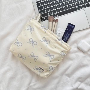 Macro detail of floral makeup bag with blue ribbon pattern on beige fabric