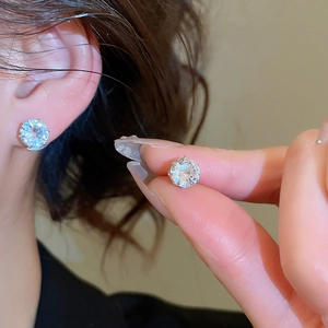 Close-up of minimalist round crystal stud earrings worn by a model in natural light