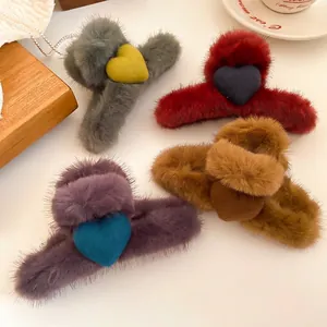 Winter plush heart hair claw clips in four colors on a decorative tabletop setup