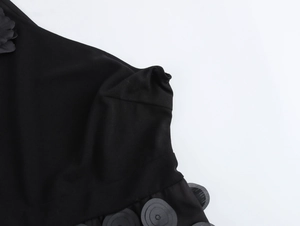 Dettaglio macro della decorazione floreale 3D sulla spalla dell'abito in rete nero