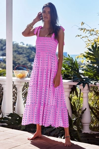 Detail of vibrant pink smocked dress with green patterns and bow ties on the balcony