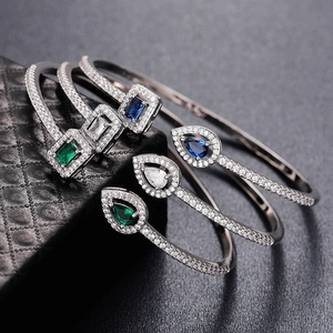 Macro shot of silver open bracelets featuring emerald and sapphire water drop stones