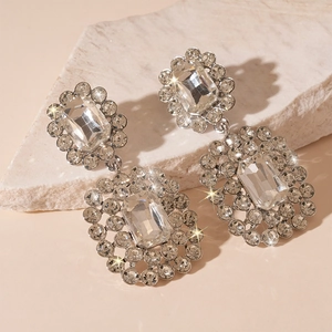 Close-up of luxury crystal earrings on beige stone with starburst lighting effect