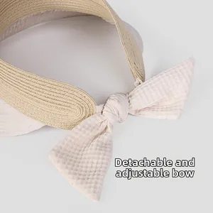 Dettaglio del fiocco rimovibile in tessuto su cappello da sole in paglia naturale