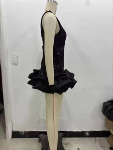 Détail de robe courte noire à paillettes sans manches avec jupe à volants étagés
