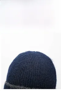 Dettaglio macro del berretto invernale in maglia blu scuro con trama calda e spessa