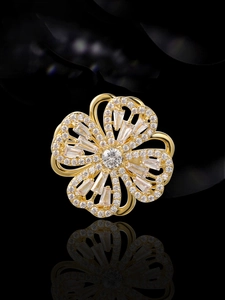 Makroaufnahme der rotierenden goldenen Blumenbrosche mit weißen Zirkonia auf schwarzem Grund