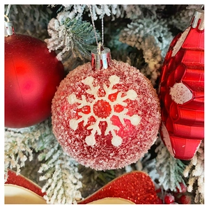 Detail of red Christmas ball with white snowflake pattern and sugar frosted texture on tree