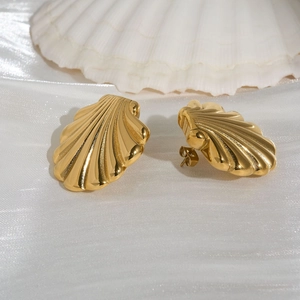 Elegant gold shell stud earrings on white silk background with a natural seashell