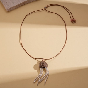 Long collier ethnique avec pendentif en noix et pompons de perles blanches sur fond beige