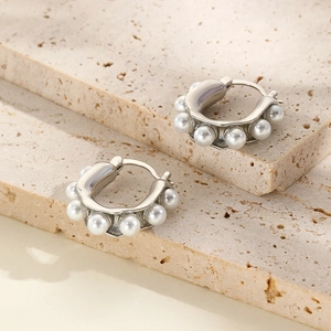 Elegant silver U-shaped hoop earrings with white pearls on a marble stone background