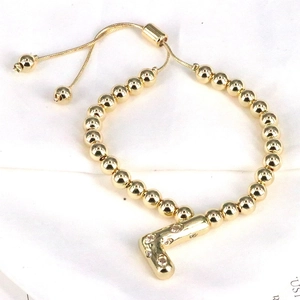 Adjustable gold bead bracelet with crystal-encrusted letter L pendant on a white background