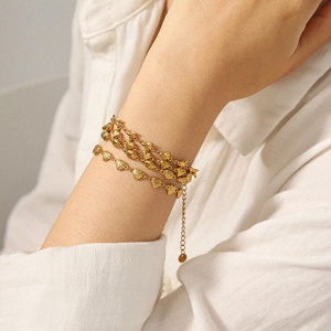Bracelet à maillons cœur en or 18k porté par un mannequin avec chemise en lin