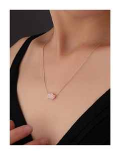 Close-up of a double heart necklace with a pink gemstone and zircon pavé on a model