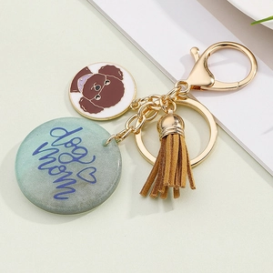 Close-up of golden keychain with dog mom glitter charm and brown suede tassel detail