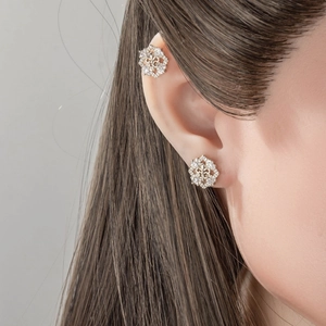 Silver iris flower stud earring with rhinestones shown on earlobe and cartilage