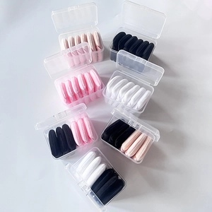 Macro shot of assorted black, white, and pink velvet triangular powder puffs in clear cases