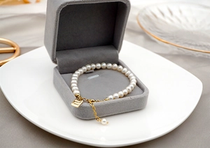 Detailed shot of freshwater pearl bracelet with Good Luck gold tag and lobster clasp