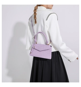 Close-up of lavender crossbody bag with woven texture on a white blazer model