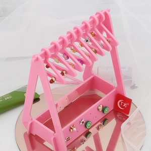 Pink acrylic jewelry display stand with clothes hanger hooks and a hollow tray organizer